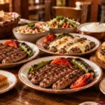 Ahşap masada sade, kaşarlı ve acılı İnegöl köfte tabakları, ekmek arası köfte, piyaz, salata, yoğurt, patates, tatlılar ve ayran